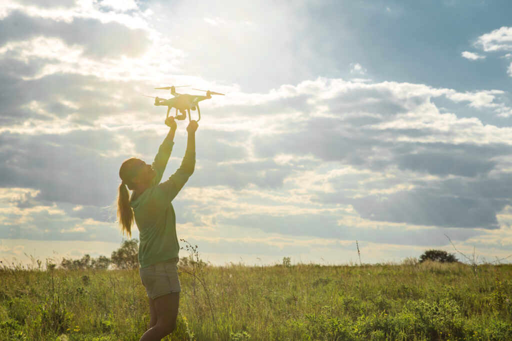 Una mujer preparando su dron para iniciar el vuelo en el campo
